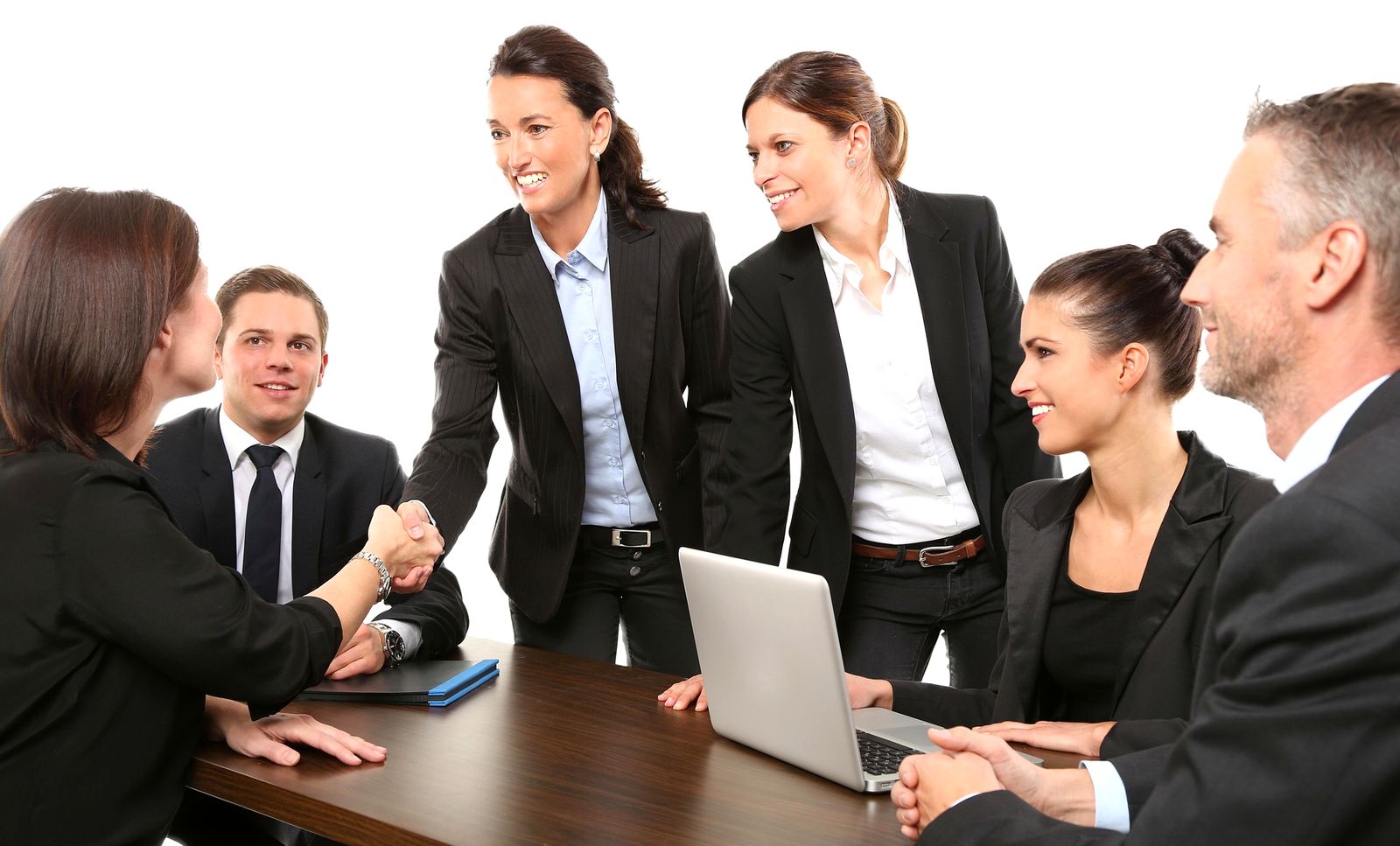 Smiling colleagues shaking hands at a meeting table